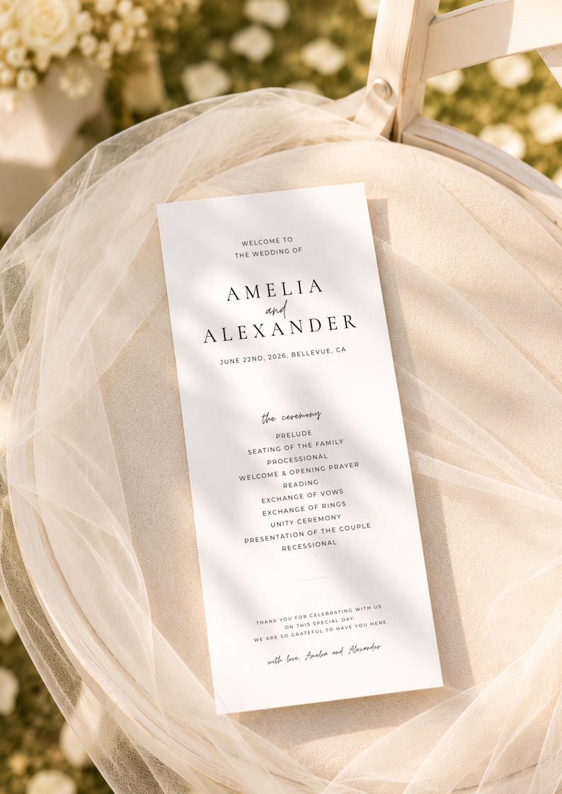Puede incluir: Un programa de boda blanco con texto negro, con los nombres "Amelia y Alexander" y la fecha 22 de junio de 2026. El programa detalla el orden de la ceremonia, incluyendo preludio, votos y procesi&oacute;n. El programa est&aacute; colocado sobre una silla cubierta con tela transparente.