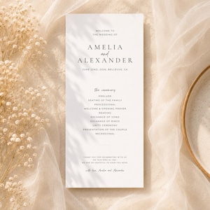 Puede incluir: Un programa de boda con los nombres Amelia y Alexander, y la fecha 22 de junio de 2026. El programa detalla la ceremonia, incluyendo el preludio y los votos. El fondo es beige suave.