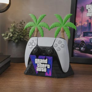 Peut inclure: Une manette de jeu vidéo blanche et noire posée sur un support noir à texture de briques. Le support présente un logo Grand Theft Auto VI violet et bleu ainsi que deux palmiers verts s'élevant à l'arrière de la base de la manette.