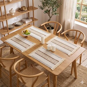 Puede incluir: Una mesa de comedor de madera con cuatro manteles individuales tejidos, cada uno con un patrón geométrico beige y marrón. La mesa está rodeada de sillas de madera con asientos tejidos. Velas y un frutero sobre la mesa.