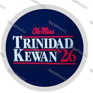 May include: A circular button with a dark blue background featuring the red text Ole Miss at the top. Below this, the white text TRINIDAD KEWAN appears in a bold serif font, followed by the red number 26, all accented by horizontal red lines.
