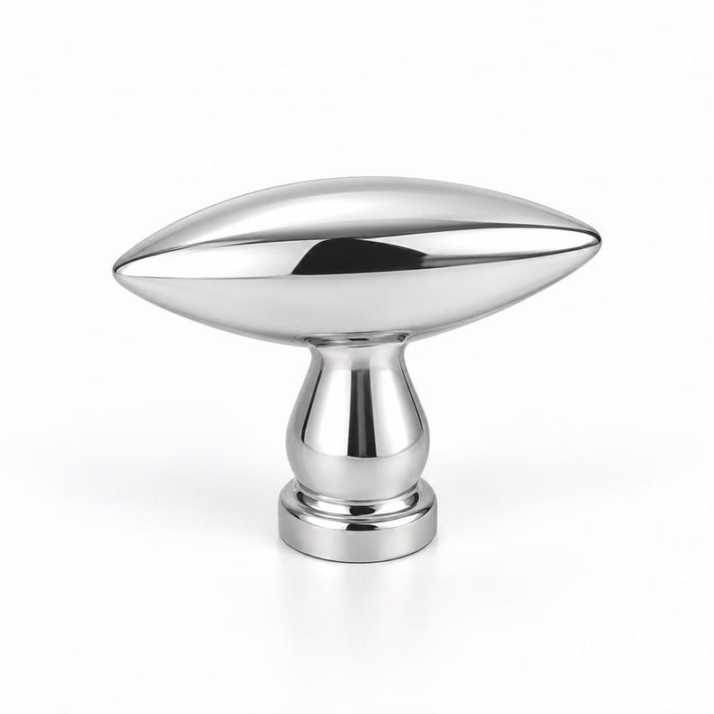 May include: A polished chrome cabinet knob featuring a horizontal, elongated, almond-shaped handle mounted on a rounded, pedestal-style base. The metallic surface is highly reflective, showing smooth, curved contours and a bright, silver-toned finish.