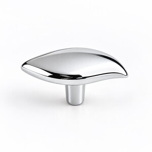 May include: A polished chrome cabinet knob featuring a smooth, elongated, leaf-like shape that tapers to a point on one side. The hardware has a reflective, mirror-like finish and a cylindrical base that connects to the main body of the knob.