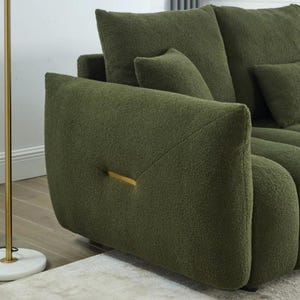 Puede incluir: Sof&aacute; boucl&eacute; verde oliva con cojines a juego. El sof&aacute; presenta un dise&ntilde;o moderno con un acento dorado en el reposabrazos. La textura afelpada y el color crean una est&eacute;tica acogedora y atractiva.