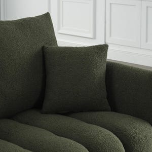 Puede incluir: Primer plano de un sof&aacute; verde oscuro texturizado con dos cojines cuadrados a juego. El sof&aacute; tiene un dise&ntilde;o curvo y una apariencia suave y afelpada. Los cojines est&aacute;n colocados en el sof&aacute;, creando un aspecto acogedor.
