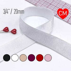 May include: A white elastic band measuring 3/4 inches wide, shown with a ruler for scale. Two small red heart-shaped pins are visible to the left. Below the band are six circular color swatches in black, white, beige, maroon, red, and light pink.