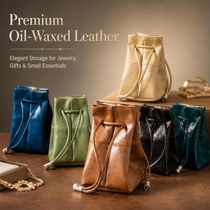 May include: A collection of six small drawstring pouches made of oil-waxed leather in various colors including blue, green, tan, brown, and black. Each pouch features a vertical seam, a drawstring closure with metal tips, and a structured base.