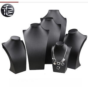 May include: A collection of black jewelry display busts in various sizes. One bust displays a silver necklace. The busts are arranged on a white background. The logo "TAIE" is visible in the upper left corner.