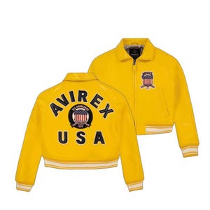 May include: A bright yellow bomber jacket with the text "AVIREX USA" on the back and a logo on the front. The jacket has a ribbed white and yellow striped hem and cuffs. The jacket has a zipper closure and a collar.