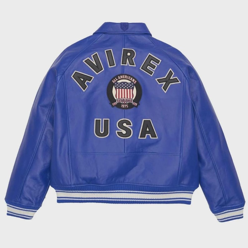 May include: A royal blue leather jacket with white and black accents. The back features the word "AVIREX" arched across the top, with "USA" below a circular patch with an American flag design. The jacket has a classic bomber style.