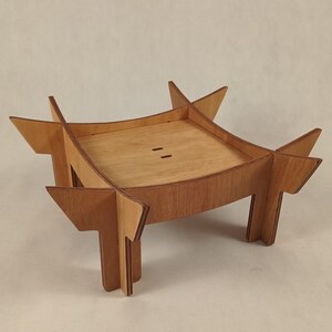 May include: A wooden, geometric side table with a square top and four legs. The table is made of light brown wood and has a unique, angular design. The table measures approximately 12 inches in length, 12 inches in width, and 6 inches in height.