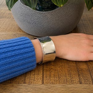 Modern 925 sterling silver wide cuff bracelet with a sleek polished finish and bold minimalist design. This chunky silver arm cuff features an open adjustable style for a comfortable fit, making it perfect for everyday wear or special occasions. The reflective statement bangle adds contemporary elegance to any outfit and pairs beautifully with casual or dressy looks. A timeless silver cuff bracelet for women and a thoughtful gift for birthdays, anniversaries, or holidays.