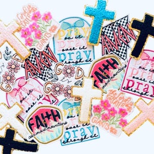 May include: A collection of embroidered patches with religious themes. The patches feature crosses, floral designs, and inspirational phrases like "Pray," "Faith," and "Good is." Colors include pink, blue, black, and white with gold trim.