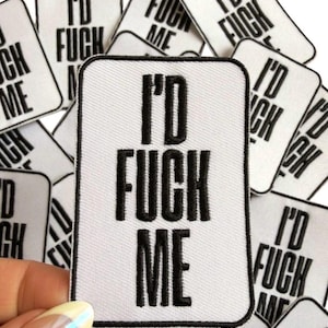 May include: White rectangular patch with the text "I'D FUCK ME" in black, surrounded by a black border. Multiple patches are visible, some overlapping. The patches are held by a hand.