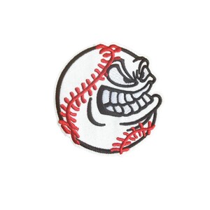 May include: A white baseball patch with red stitching and a black outline. The patch features a cartoon face with a wide, toothy grin, giving it an aggressive appearance. This patch is suitable for sports fans.
