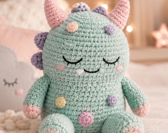 May include: A handmade crochet dinosaur plush toy in soft teal, with pink and purple accents. The toy has closed eyes and a gentle smile. Pastel-colored spots adorn its body. Other plush toys and decorative lights are in the background.