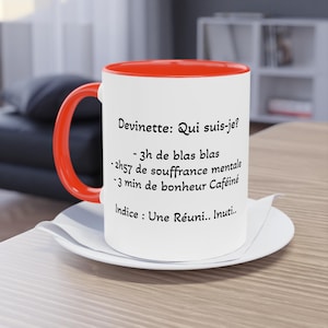 May include: A white ceramic mug with a bright orange handle and interior rim. The mug features black printed French text: Devinette: Qui suis-je? - 3h de blas blas - 2h57 de souffrance mentale - 3 min de bonheur Caféiné Indice : Une Réuni.. Inuti..