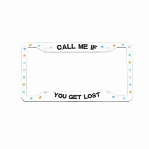May include: A rectangular white license plate frame featuring the black text CALL ME IF YOU GET LOST. The frame is decorated with a repeating pattern of small, colorful stars in shades of pink, yellow, and light blue along the entire border.
