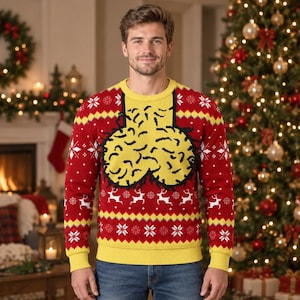 May include: A long-sleeved crewneck sweater featuring a red base with yellow and white patterns. The design includes a large yellow graphic on the chest, white reindeer and snowflake motifs, and yellow ribbed trim at the collar, cuffs, and hem.