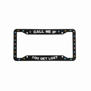 May include: A black rectangular license plate frame featuring the white text CALL ME IF YOU GET LOST. The frame is decorated with small, multi-colored stars in shades of pink, blue, and orange spaced evenly along the entire border of the frame.