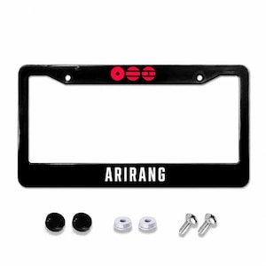 May include: Black license plate frame with the word "ARIRANG" in white lettering. The top of the frame has a red graphic. Includes mounting hardware: screws, washers, and black screw caps.