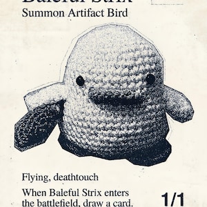 Op de afbeelding: Een donkerblauw gehaakt vogelbeeldje gecentreerd op een crèmekleurige kaart met de tekst Baleful Strix, Summon Artifact Bird, Flying, deathtouch, When Baleful Strix enters the battlefield, draw a card, 1/1, C 0088, SLZ EN MSCHF en UB.