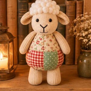 Pu&ograve; includere: Un peluche a forma di pecora con testa e arti in maglia color crema, caratterizzato da una parte superiore con pompon bianchi testurizzati. Il busto &egrave; realizzato in tessuto patchwork, con un motivo floreale sopra e un design a quadretti rossi e pois verdi.