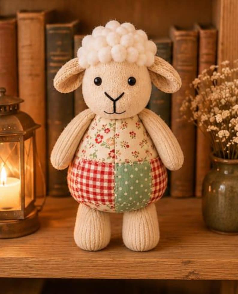 Pu&ograve; includere: Un peluche a forma di pecora con testa e arti in maglia color crema, caratterizzato da una parte superiore con pompon bianchi testurizzati. Il busto &egrave; realizzato in tessuto patchwork, con un motivo floreale sopra e un design a quadretti rossi e pois verdi.