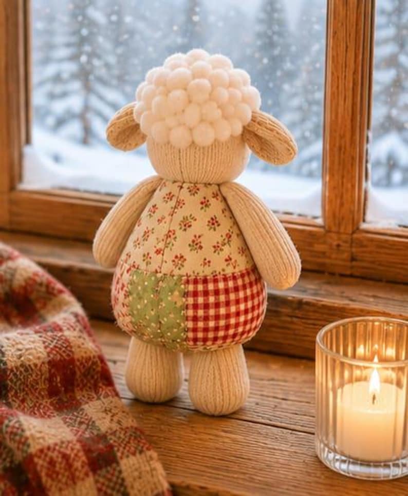 Pu&ograve; includere: Un peluche a forma di pecora con testa fatta di pon pon bianchi, braccia e gambe in tessuto a coste beige e un busto caratterizzato da un design patchwork con tessuto floreale, tessuto verde fantasia e un motivo a quadri rossi e bianchi.