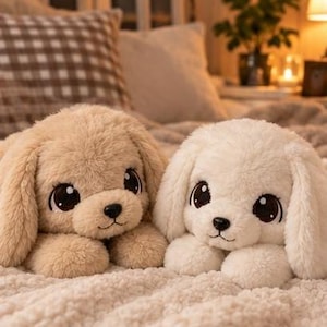 May include: Two plush dog toys with soft, fuzzy fur. One dog is light tan and the other is cream white. Both feature large, dark brown, glossy eyes, small black noses, and long, floppy ears. They are positioned side by side in a lying position.