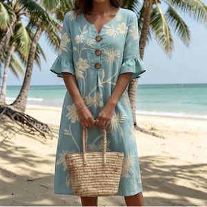 Peut inclure: Une robe midi bleu clair ornée de broderies florales blanches, dotée de manches trois-quarts à volants, d'une encolure en V et de trois boutons marron sur le devant. La robe est accompagnée d'un sac cabas en paille tressée à anses.