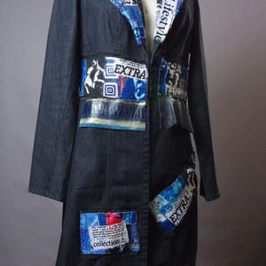 May include: A dark denim coat featuring a notched collar and waist panels adorned with blue fabric patches, newspaper-style text prints reading "Fashion," "Lifestyle," "EXTRA," and "collection," and textured dark blue leather-like accents.
