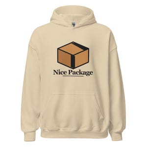 Könnte beinhalten: Ein cremefarbener Kapuzenpullover mit einer Grafik eines braunen Pappkartons mit schwarzen Umrissen. Unter dem Karton ist der Text "Nice Package" in einer fetten schwarzen Serifenschrift gedruckt, mit einer horizontalen schwarzen Linie darunter.