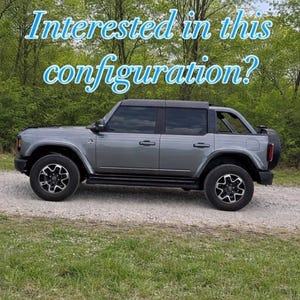 May include: A grey four-door SUV with a black roof and tinted windows, featuring a spare tyre mounted on the rear. The text "Interested in this configuration?" is overlaid in light blue letters against a background of green trees.
