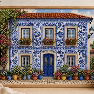 May include: A framed cross-stitch embroidery depicting a two-story house with blue and white tile patterns, a terracotta roof, and a central blue door. The facade features five windows with flower boxes, climbing vines, and potted plants on the ground.