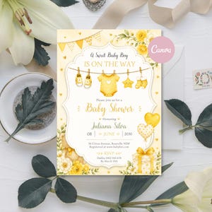 Puede incluir: Una tarjeta de invitación para baby shower en amarillo y blanco con ilustraciones en acuarela de ropa de bebé en un tendedero, flores amarillas y globos. El texto dice A Sweet Baby Boy IS ON THE WAY, Baby Shower, Juliana Silva, 08 JUNE 2030 y detalles de RSVP.