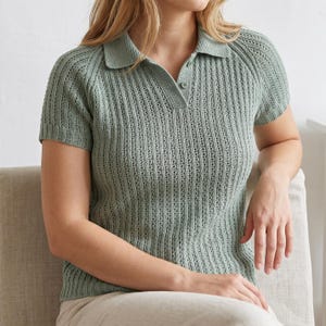 May include: A light green polo shirt with short sleeves. The shirt has a collared neckline and a buttoned placket. The fabric has a textured, vertical ribbed pattern. The shirt is made of a soft, breathable material, perfect for warm weather.