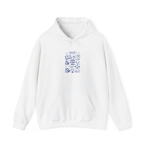 Op de afbeelding: Een witte hoodie met een voorzak en een capuchon met trekkoord. De hoodie heeft een blauwe afbeelding met de tekst "READER'S GAME DAY NOTES" en illustraties van hockey-gerelateerde items.