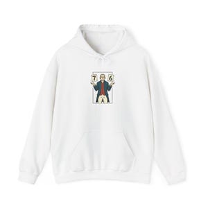 Op de afbeelding: Witte hoodie met een voorzak en een trekkoord. De afbeelding op de voorkant toont een cartoonillustratie van een man die kaarten vasthoudt met de nummers 7 en 6. De man draagt een rode jas en een witte pruik.