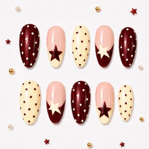 May include: A set of ten artificial nails in various designs. Some nails are burgundy with white polka dots, others are pale yellow with dark dots, and some have a pink and burgundy star design. Small star and bead embellishments surround the nails.