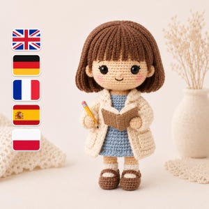 Puede incluir: Muñeca de ganchillo hecha a mano de una persona con cabello castaño, vestida con un vestido azul, un abrigo color crema y zapatos marrones. La muñeca sostiene un pequeño libro marrón y un lápiz amarillo. La muñeca es un profesor o estudiante.