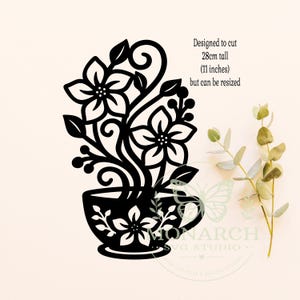 Op de afbeelding: Een zwart silhouetontwerp van een theekopje gevuld met krullende bloemstengels en bladeren. De tekst luidt: Designed to cut 28cm tall (11 inches) but can be resized. Het ontwerp bevat twee grote bloemen en kleine besjes op de kop.