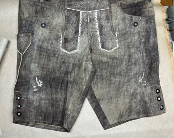 Könnte beinhalten: Braune Lederhose mit Gürtel und Ziernähten. Die Hose hat ein Used-Aussehen mit weißer Stickerei auf den Taschen und Kanten. Sie hat einen Knopfverschluss und eine dekorative Schnalle am Gürtel.