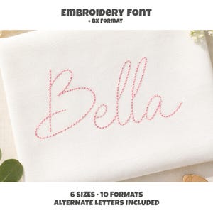 May include: A white fabric sample featuring the name Bella embroidered in a pink cursive font. The text at the top reads EMBROIDERY FONT + BX FORMAT, and the text at the bottom reads 6 SIZES 10 FORMATS ALTERNATE LETTERS INCLUDED.