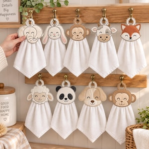 May include: A collection of nine white hand towels hanging on wooden hooks, each featuring a different embroidered animal face at the top, including an elephant, rabbit, monkey, cow, fox, sheep, panda, dog, and a second monkey design.