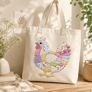 May include: A cream-colored canvas tote bag featuring a large, central applique of a chicken. The chicken is constructed from various floral and patterned fabric patches in shades of pink, yellow, blue, purple, and green with visible stitching.