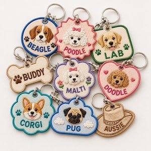 Puede incluir: Una colección de llaveros bordados con temática de perros en varias formas, incluyendo círculos, huesos, corazones y nubes. Cada llavero presenta un retrato detallado de un perro y etiquetas de texto como Beagle, Poodle, Lab, Buddy, Malti, Doodle, Corgi, Pug y Aussie.