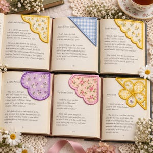 May include: Six fabric corner bookmarks placed on open book pages. The bookmarks feature various designs including yellow floral, blue gingham, scalloped yellow floral, purple floral, pink floral, and a yellow flower-shaped pattern.