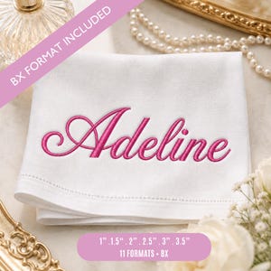 Può includere: Un tovagliolo di stoffa bianco con il nome Adeline ricamato in corsivo rosa brillante. Il testo BX FORMAT INCLUDED è visibile su una fascia diagonale rosa, e il testo 2,54 cm, 3,81 cm, 5,08 cm, 6,35 cm, 7,62 cm, 8,89 cm, 11 FORMATS + BX è riportato sotto.