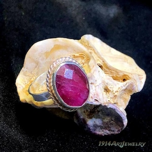 Handmade sterling silver ruby ring featuring an oval faceted ruby gemstone surrounded by a vintage rope-style bezel setting.